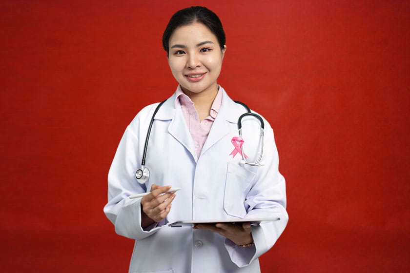Indian woman doctor in a white coat with a stethoscope, arms folded, smiling